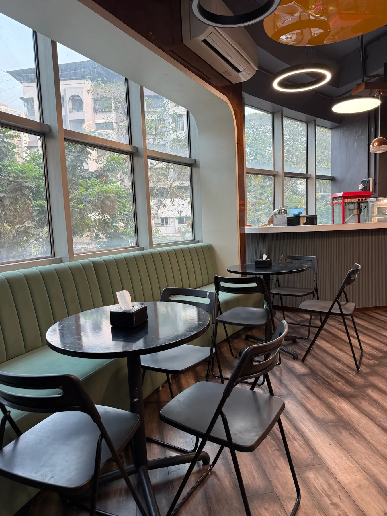 Cafe tables and chairs beside a wall of windows at Lopa Cafe